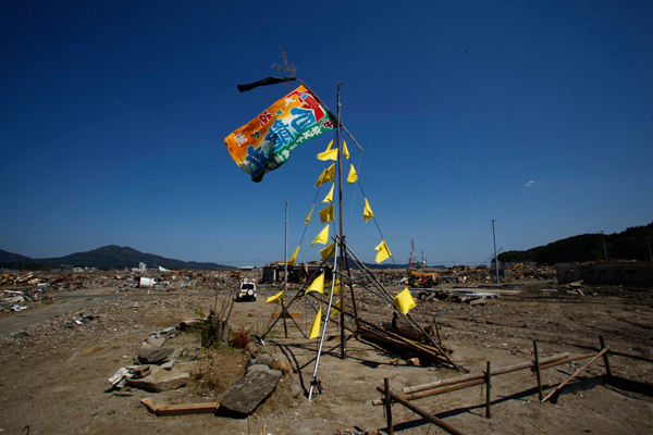 Yellow handkerchiefs fly from a temporary structure that has been erected by the owner of a derelict plot of land in Rikuzentakata, Iwate Prefecture, on March 18, 2011. Immortalized in Yoji Yamada's 1977 film “The Yellow Handkerchief,” the garments have come to symbolize a vow to return. | © Bon Ishikawa