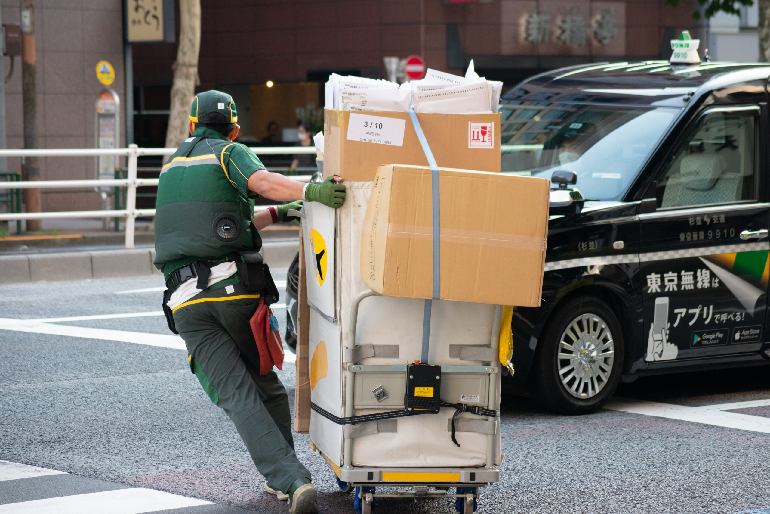 A courier pulls packages across a street in Shimbashi, Tokyo, on Aug. 21. Industries with high numbers of heatstroke cases include construction, manufacturing, security, commerce and transportation.